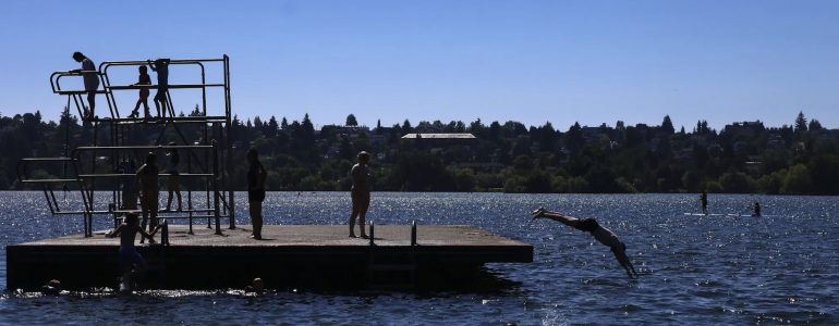 Dozens of children enjoy the water raft playground to escape the heat wave at Green Lake Park on July 9, 2024. (Audrey Richardson / The Seattle Times)